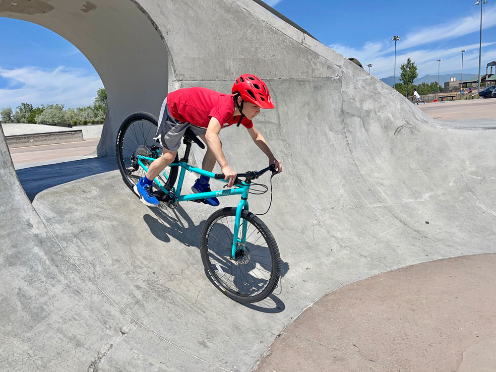 Boy riding down steep ramp at the skatepark on the Pello Roovi kids bike
