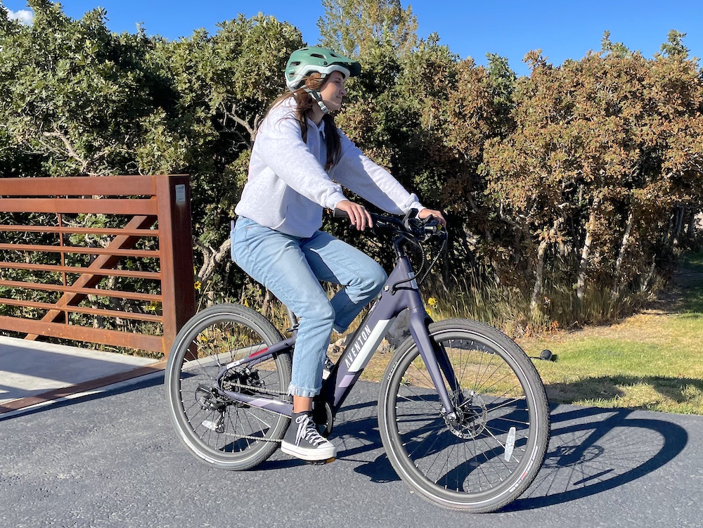 Young woman riding Aventon Pace 350 womens electric bike over a bridge