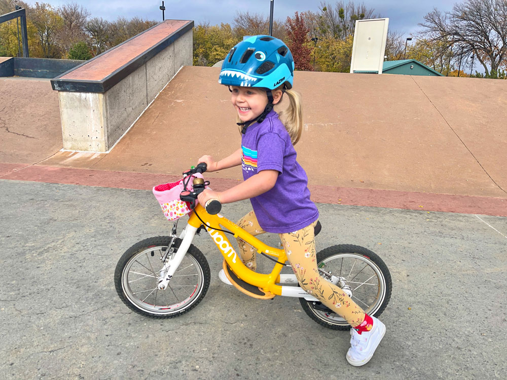 Toddler riding balance bike and wearing Lazer Pnut helmet with Shark design