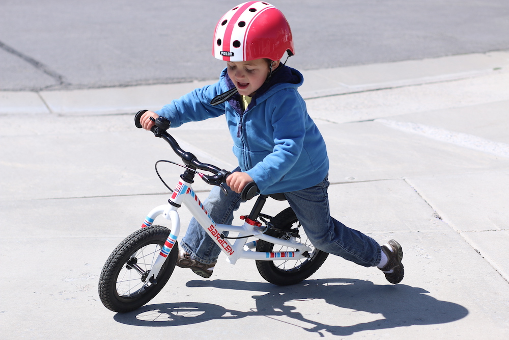 Young rider on a white Saracen freewheel balance bike turning