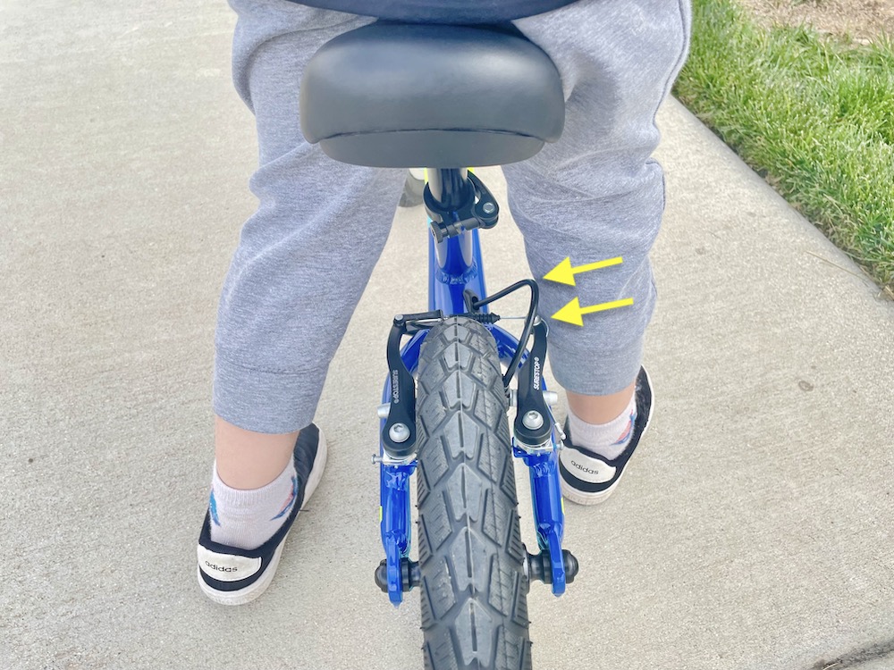 Young rider standing on the Guardian balance bike and having his leg hit the rear brake caliper
