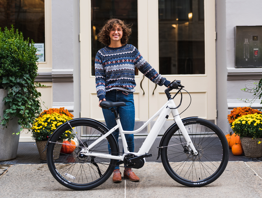 woman standing next to a white Priority Current electric bicycle