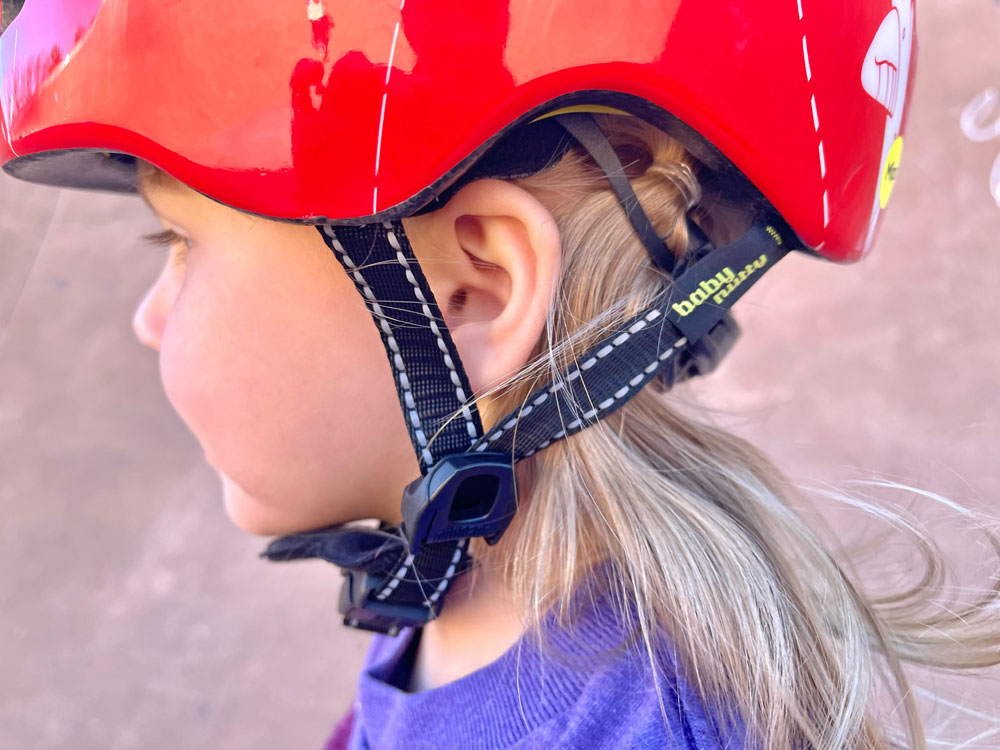 Side straps on Nutcase Baby Nutty form a V underneath a toddler's ear