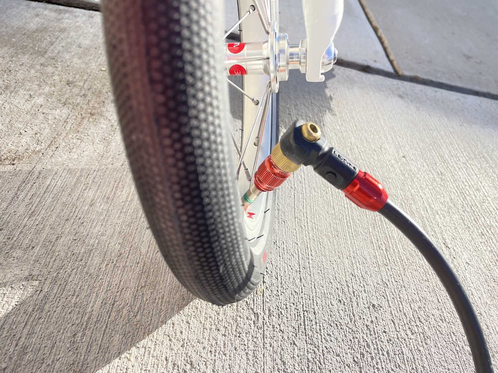 the head of a bike pump attached to the angled tire valve of the woom 1