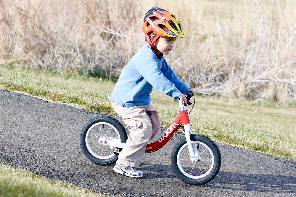 toddler riding on red woom 1 down a hill