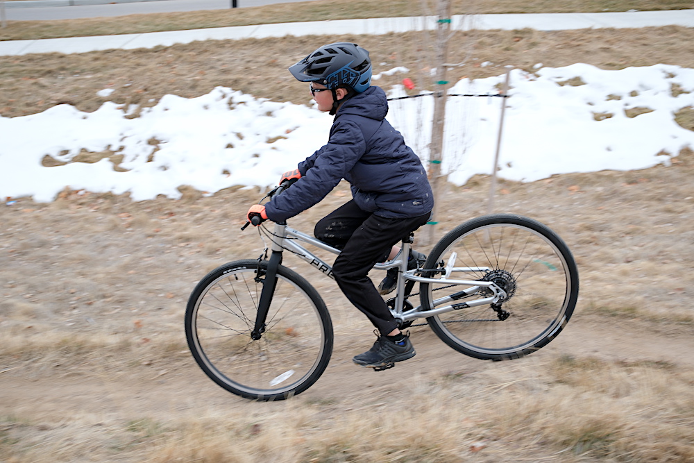 child riding the Prevelo Alpha Five 26 inch kids bike on a dirt trail