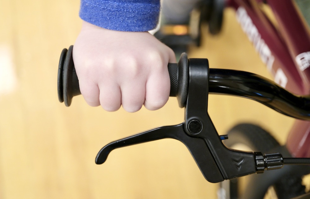 a small child holding onto the grip of the Prevelo Alpha Two 16" kids bike