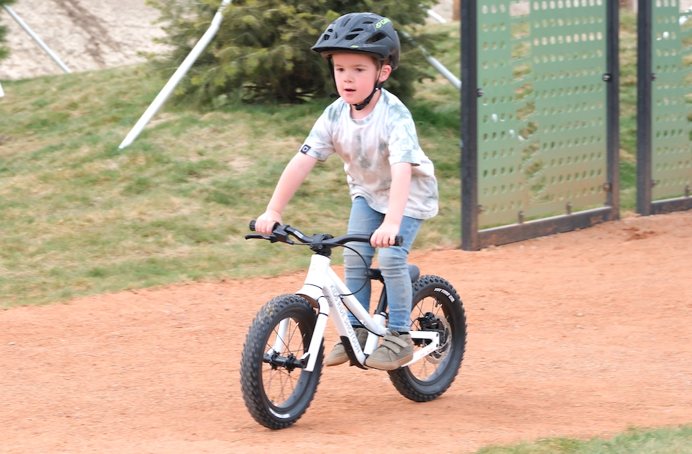boy standing up while riding on a balance bike