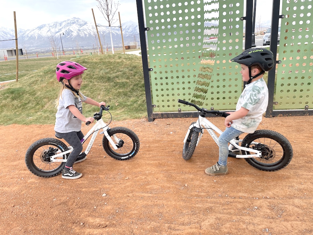 young boy and girl chatting it up while sitting on their Dirt Hero balance bikes