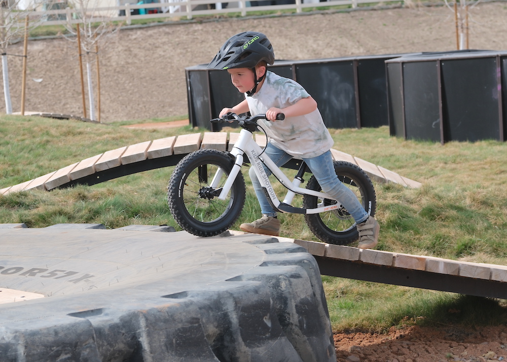 boy leaning into his balance bike while riding up a ramp