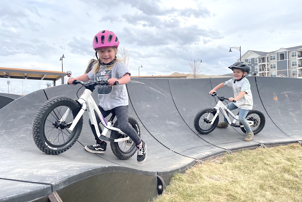 boy and girl having fun while riding their kids ride shotgun balance bikes on a pump track