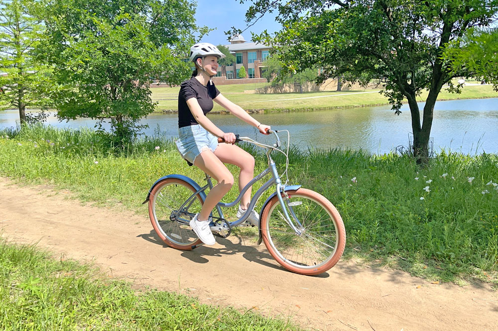 Young woman riding Priority Coast down a dirt path