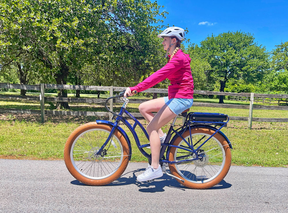 Woman rides Priority e-Coast electric bike down a country road