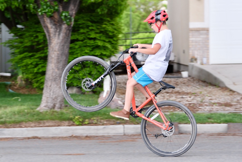 boy doing a wheelie on the Pello 27.5" kids bike