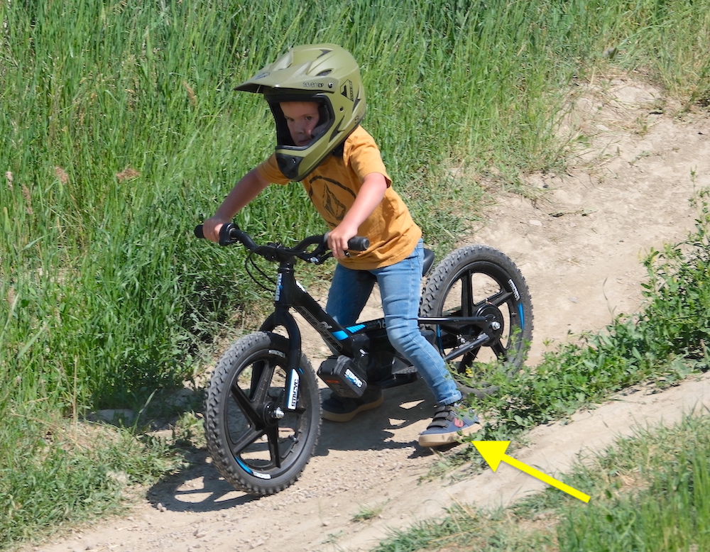 boy dragging his feet as he rides down a hill on his 16 inch stacyc