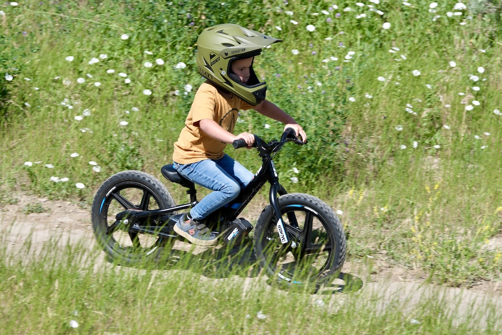 boy riding on a dirt single track trail on an electric balance bike