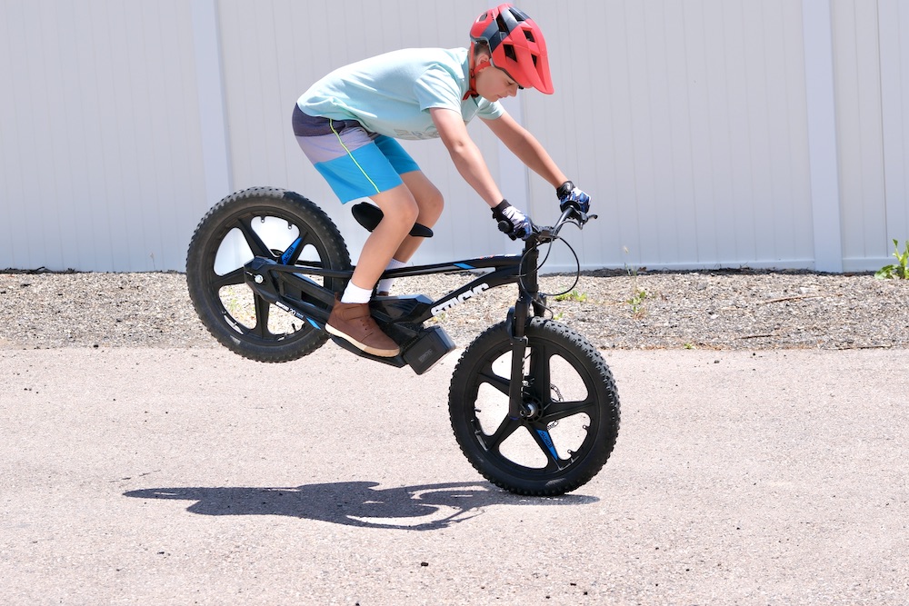 boy doing a wheelie on a 20 inch stacyc electric balance bike 