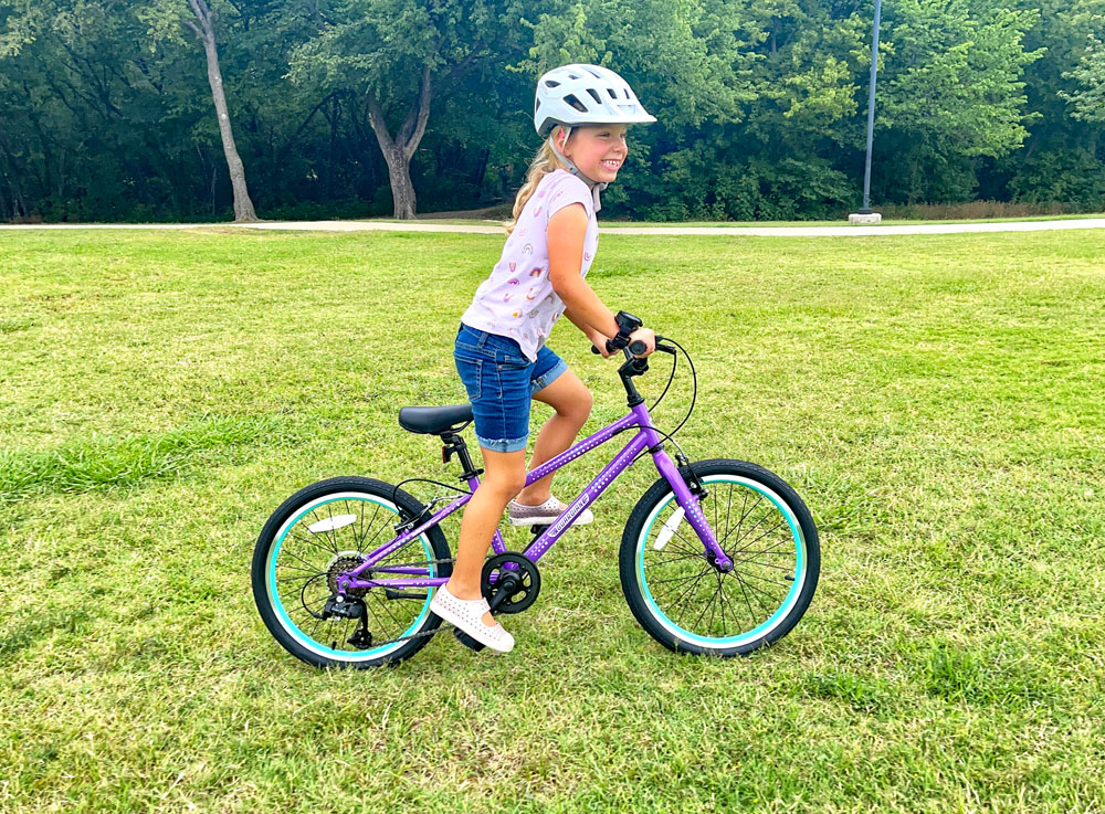 Child riding Guardian 20 inch bike across a grassy field