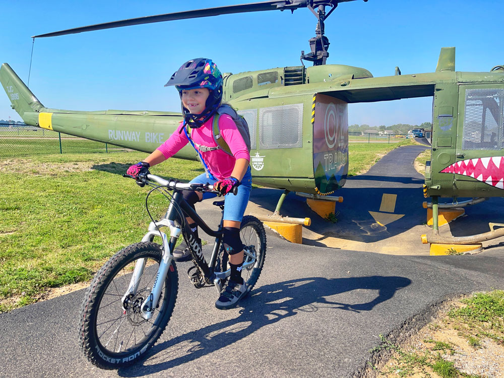 girl riding a woom OFF AIR through a an obstacle at a bike park