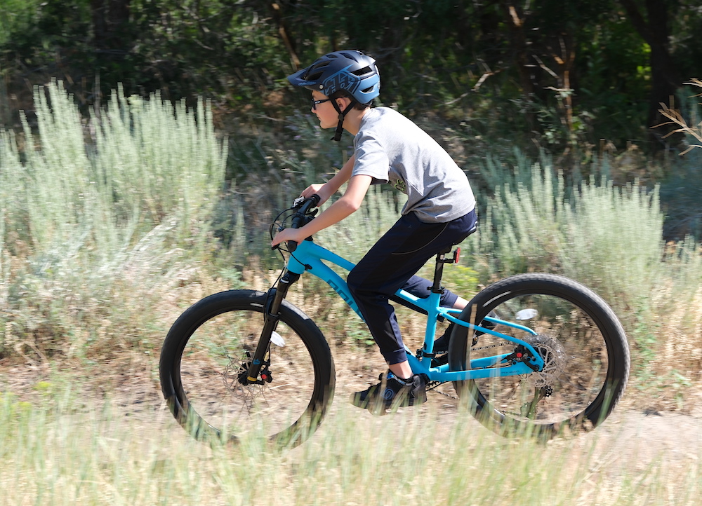 boy riding the 24 inch Polygon Xtrada 24 mountain bike on a singletrack trail