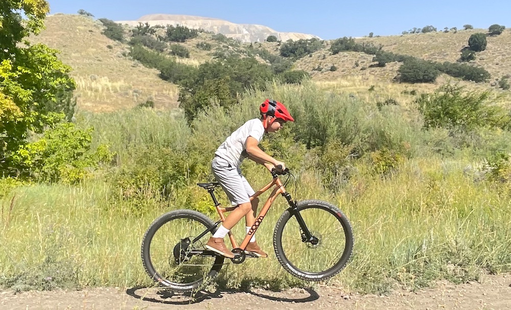 boy riding woom off air about to land a jump