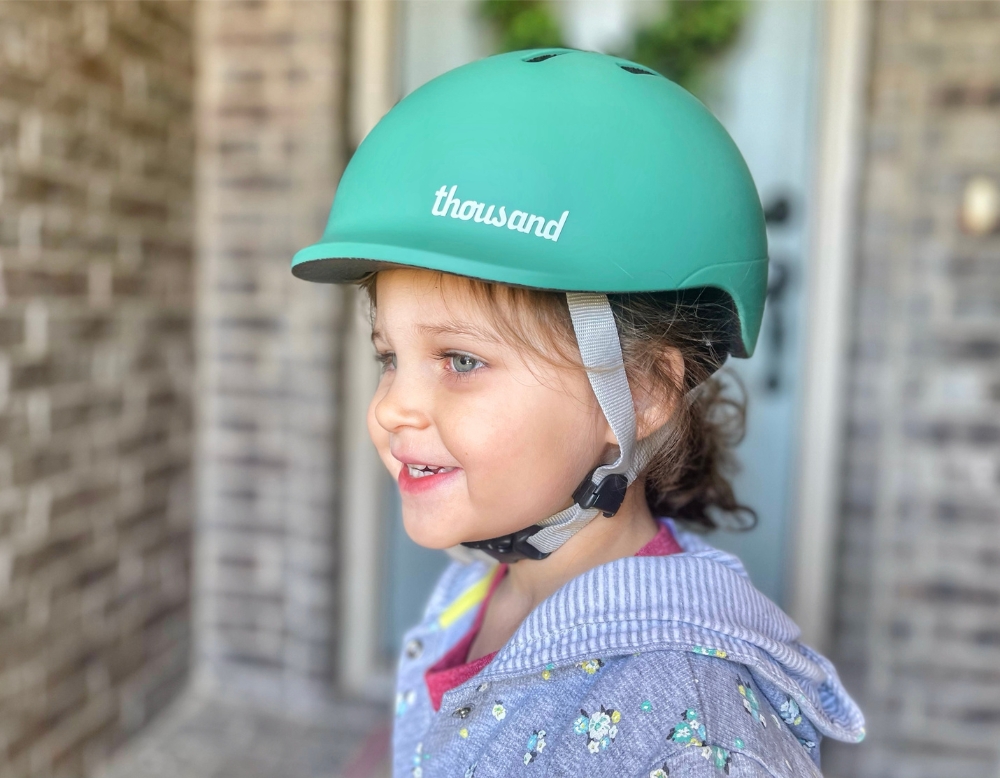 2 year old wearing Thousand Jr toddler helmet in green