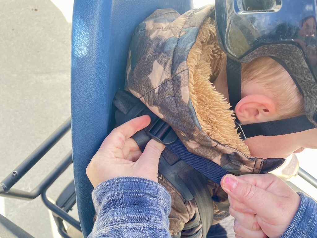 Mom adjusting the shoulder strap tightness on the Yepp 2 maxi seat