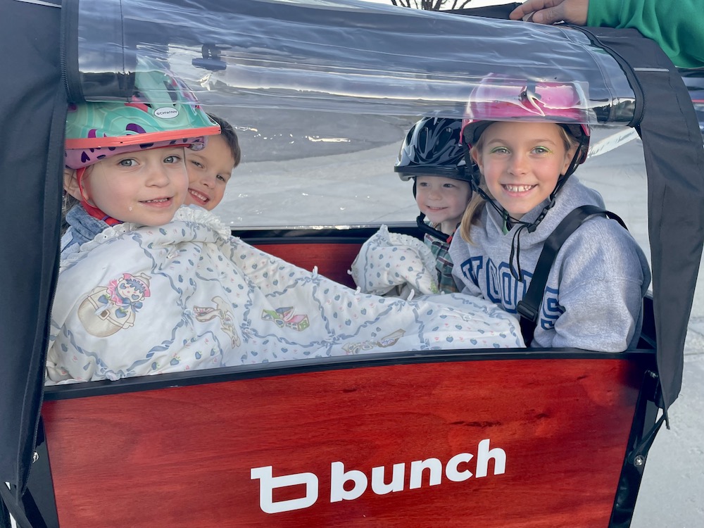 kids of all ages riding in a Bunch Bike with the canopy on