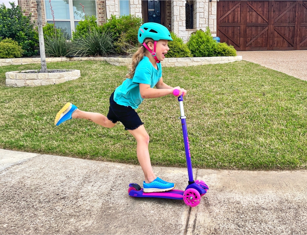 6 year old riding GoTrax 3 wheels scooter on the sidewalk