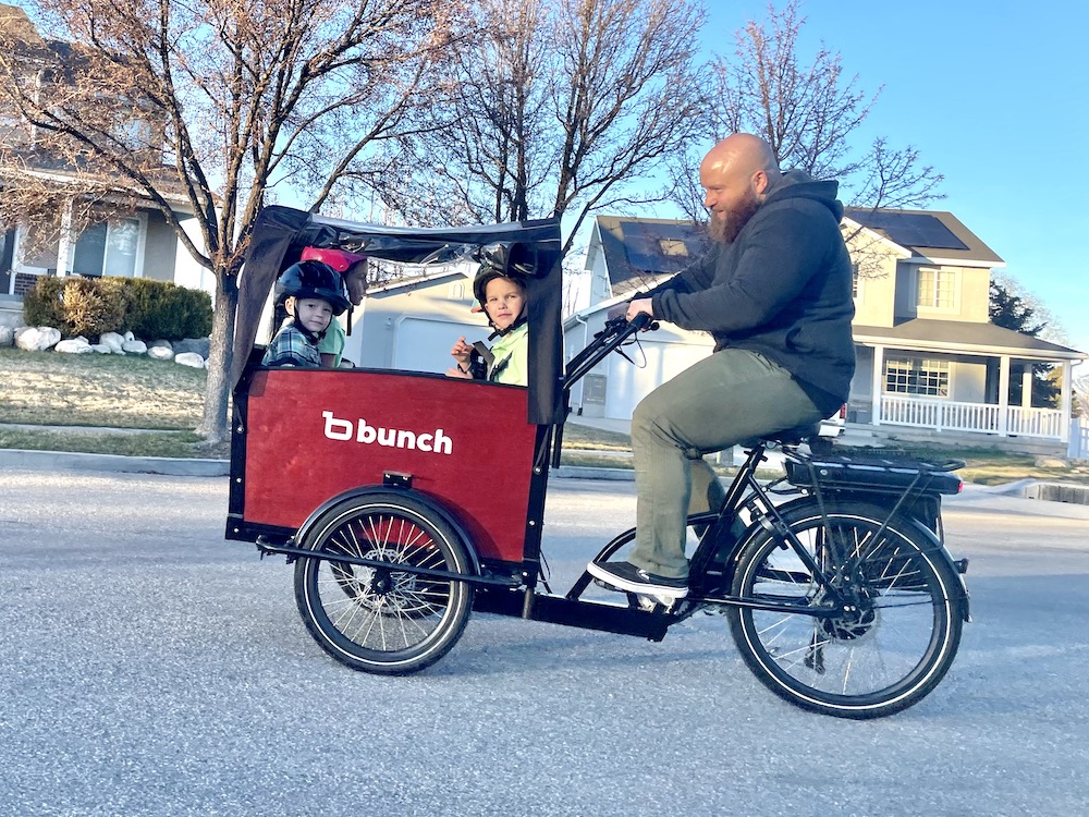 Dad riding the Bunch Bike with his kids inside