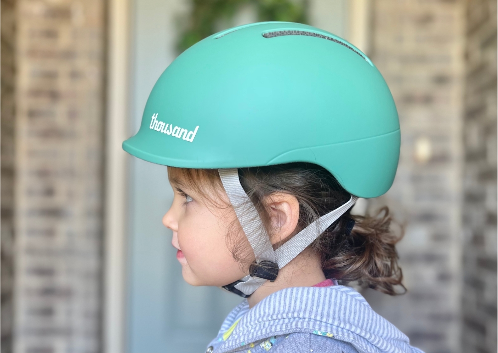 Side shot of toddler wearing Thousand Jr helmet, showing integrated visor