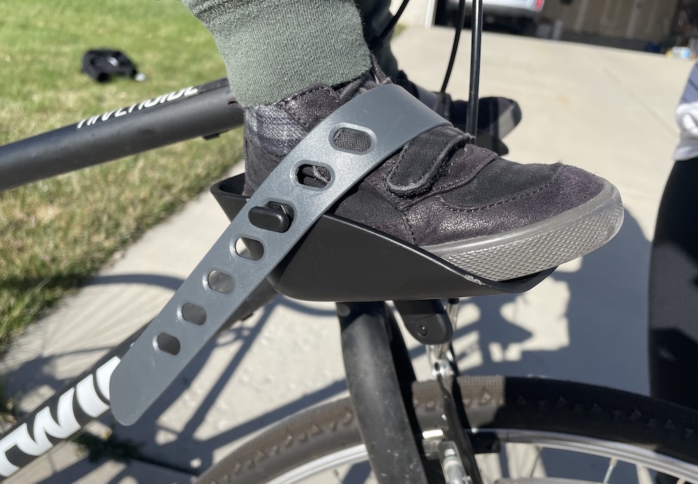 toddler's foot strapped into a footrest on a child bike seat