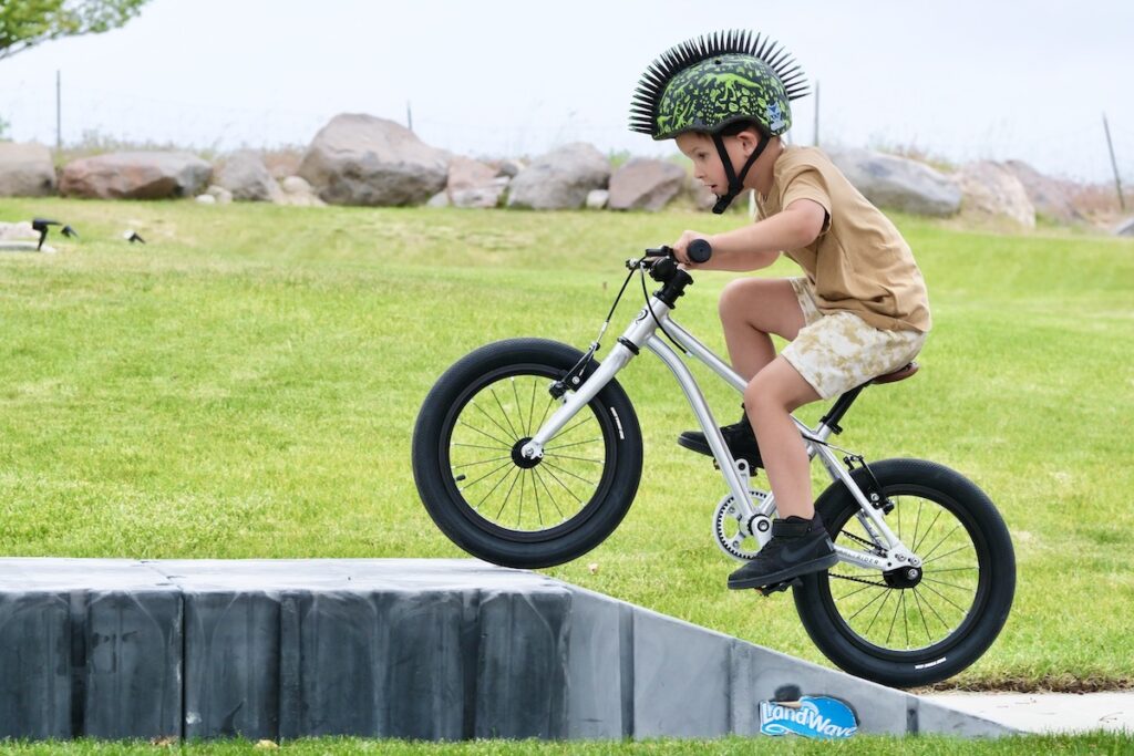 young boy riding the Early Rider Belter 16 up a ramp.