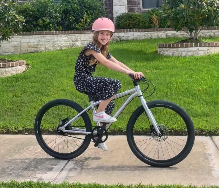 8 year old girl riding Early Rider Belter 24" kids bike down the sidewalk
