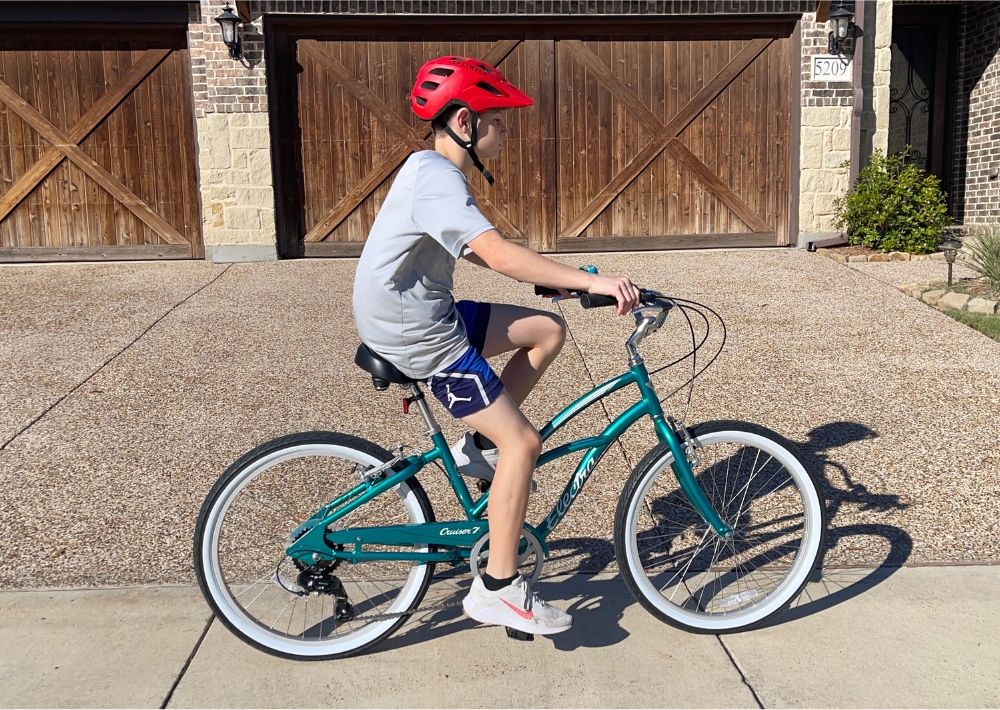 Teenager riding Electra Cruiser 24 inch bike down the sidewalk