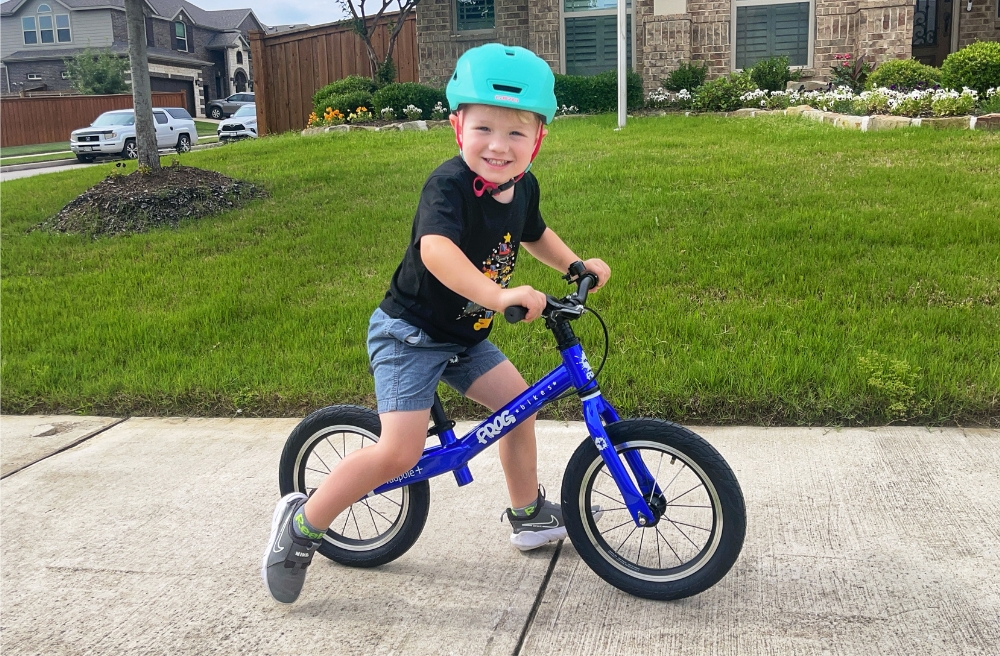 3 year old boy riding Frog Tadpole Plus balance bike on the sidewalk