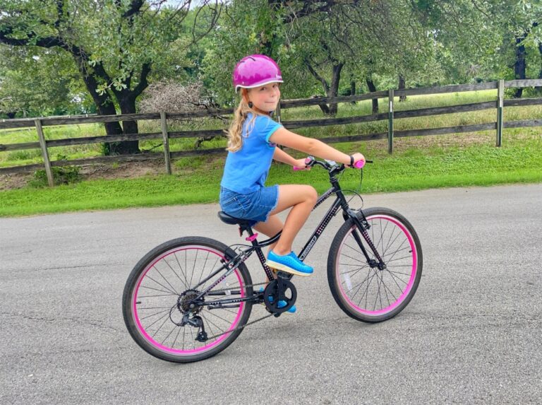 Girl riding black and pink Guardian 24 inch bike on a country road