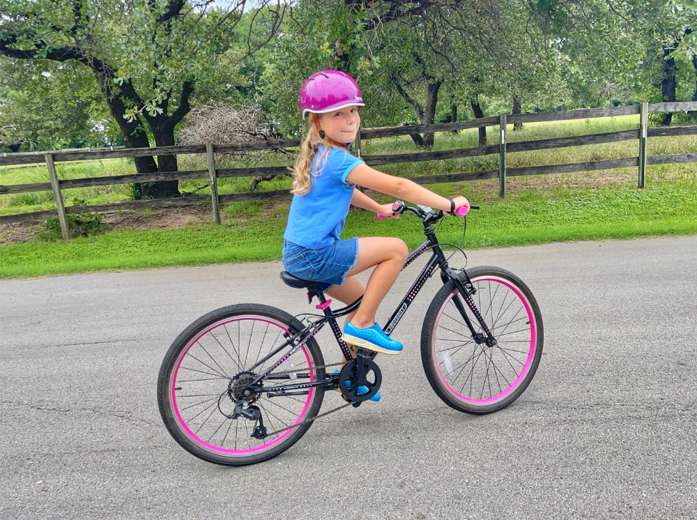 Girl riding black and pink Guardian 24 inch bike on a country road