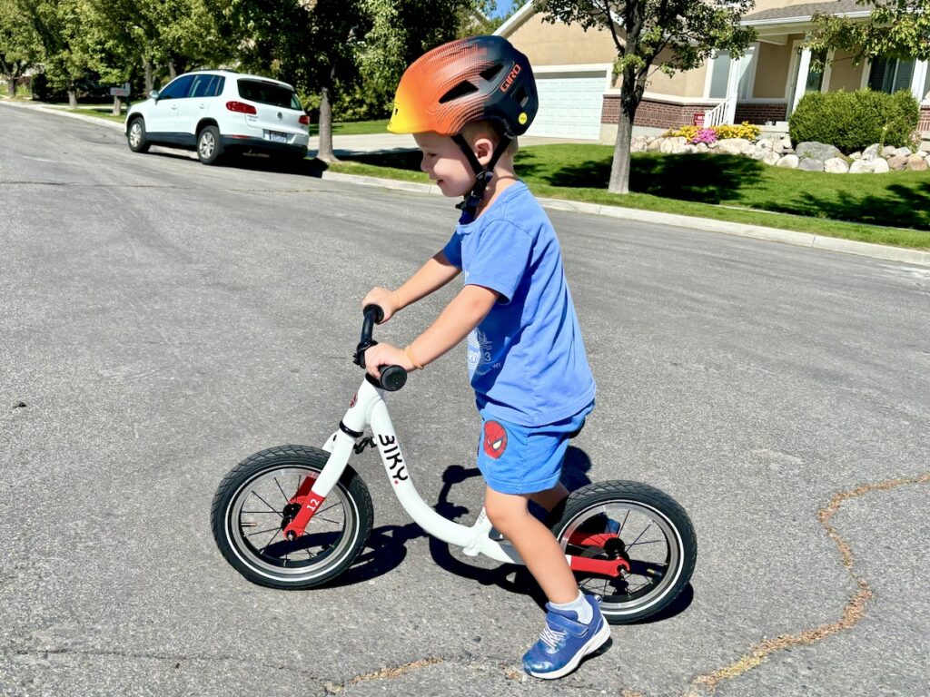 taller preschooler in 3T clothes riding te Biky 12 balance bike