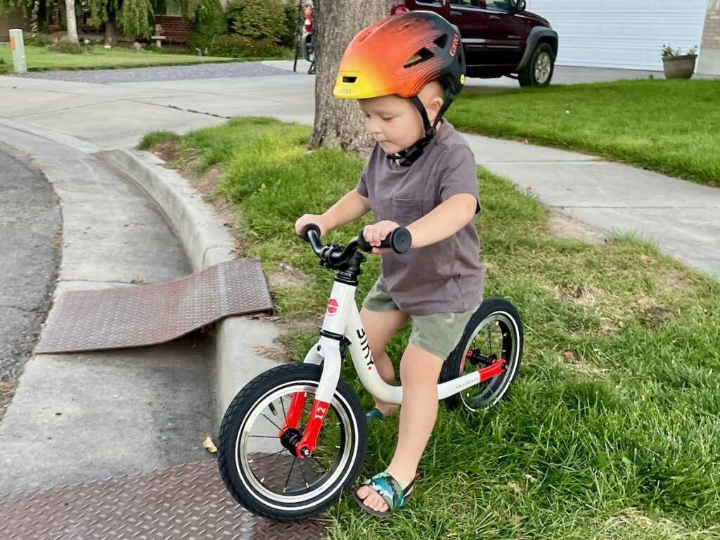 young rider riding his balance bike on grass
