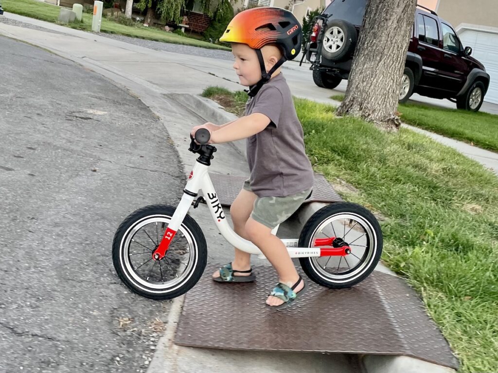 toddler riding the Biky 12 balance bike down a ramp