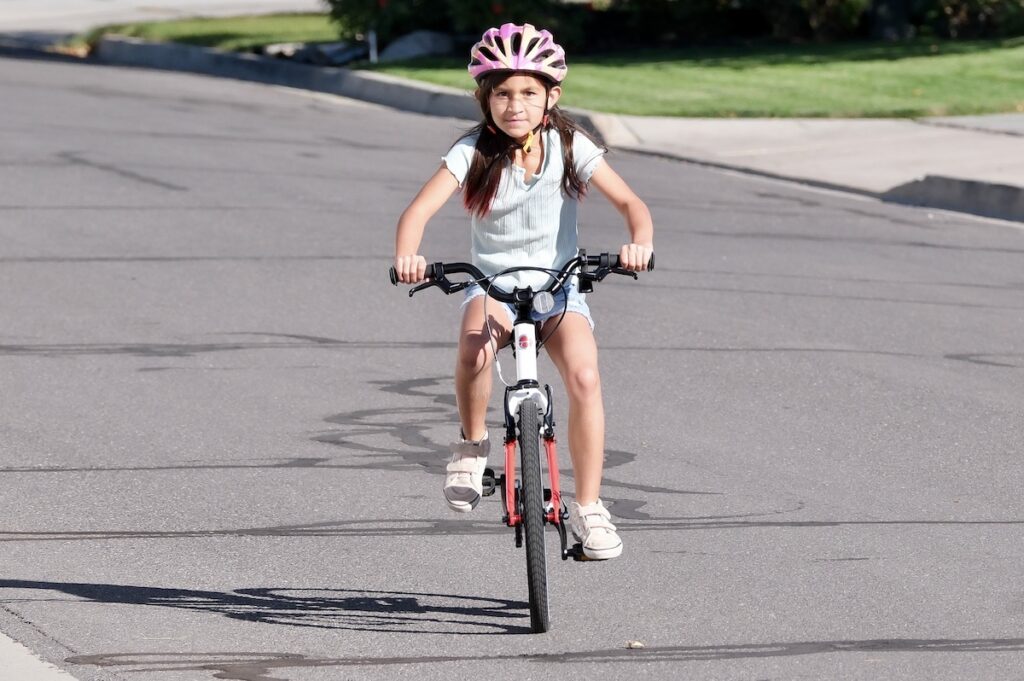 young girl on the biky 20 riding towards the camera to show the narrow build of the bike