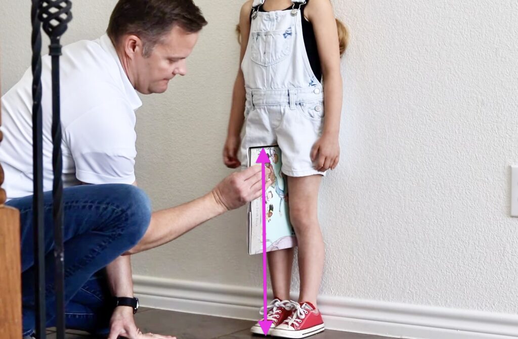 Child getting her inseams measured for a bike by using the book method