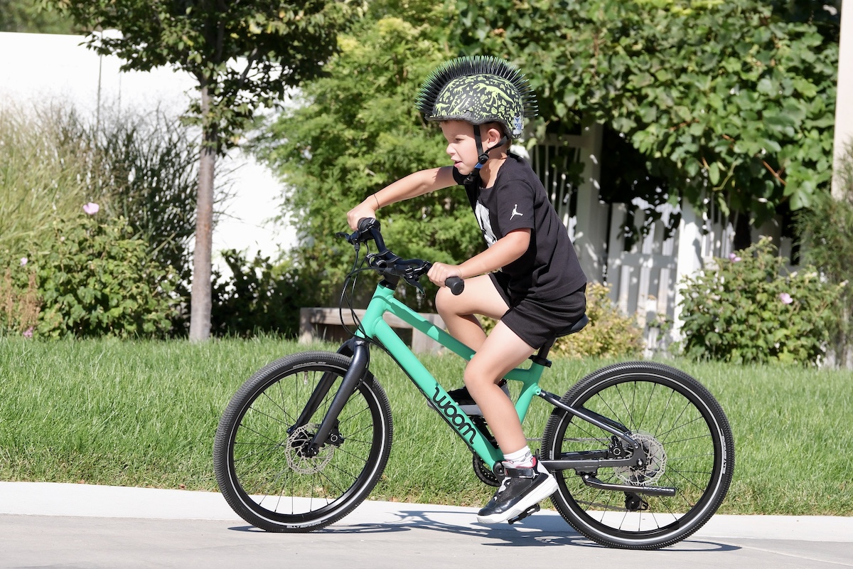 child riding a green woom 4 EXPLORE 20 inch kids bike