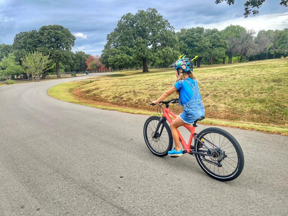 Child riding woom EXPLORE down a country road, shown from behind