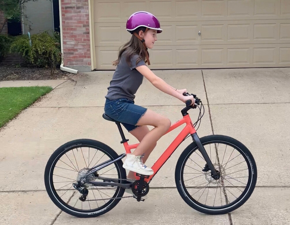 11 year old riding woom EXPLORE 5, shown from side. Mid-sized rider with saddle set to 30.75".