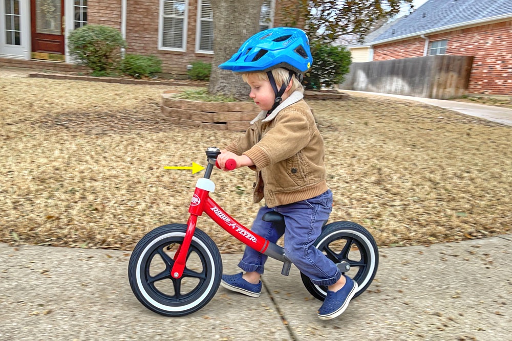 Toddler riding the Radio Flyer Air Ride balance bike with the handlebars raised