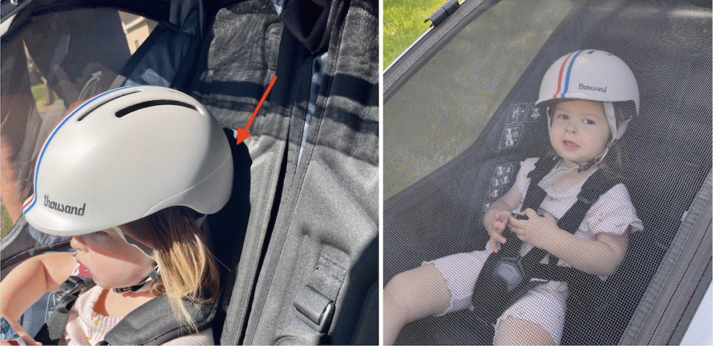 child riding in the thule chariot with her helmet being pushed forward by the seat