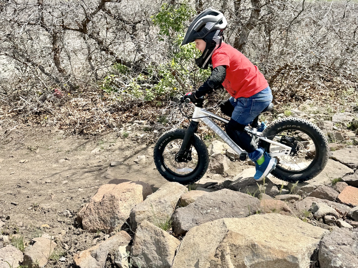 Child riding Prevelo Zulu One mountain bike in balance bike mode down a rock garden