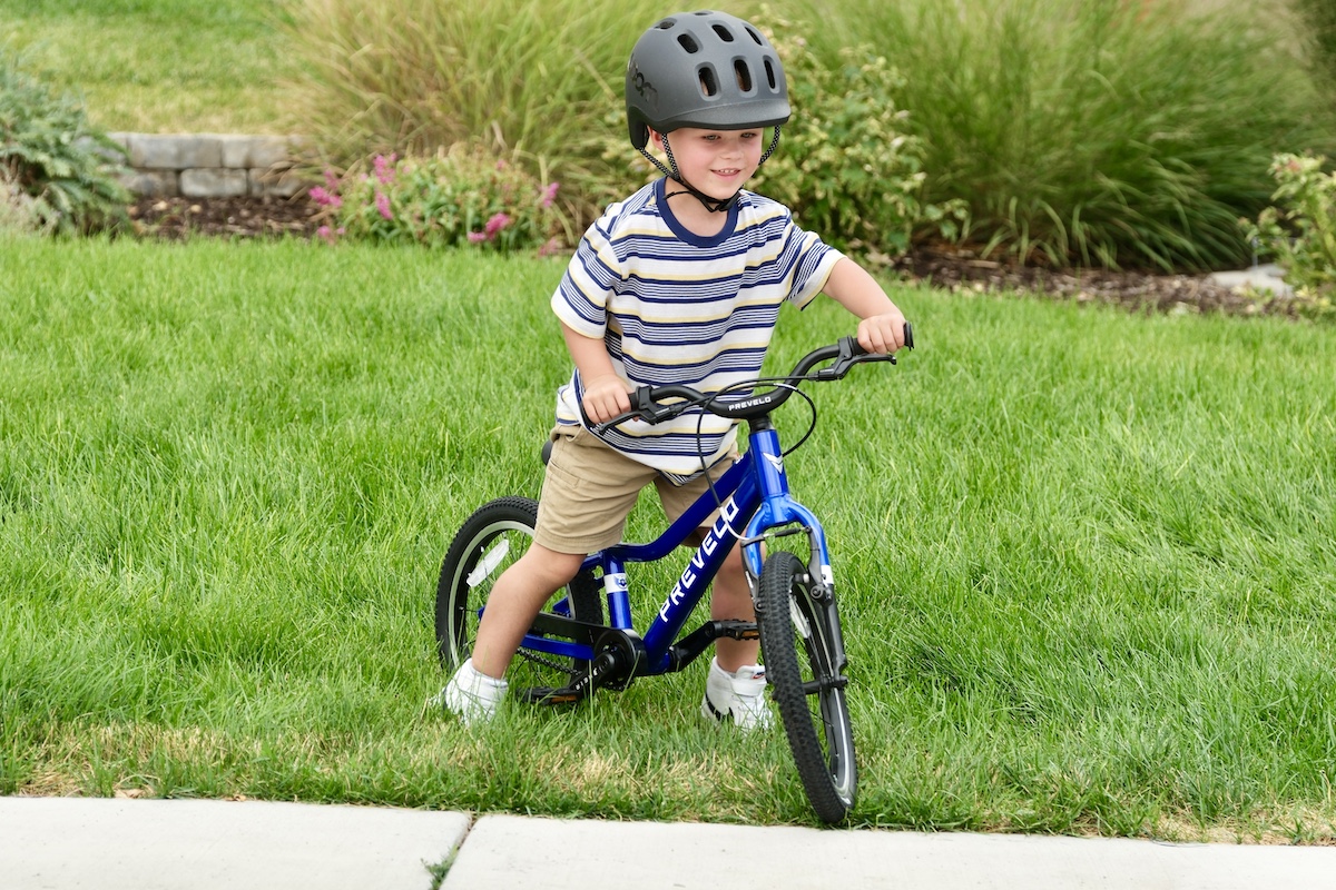 smiling preschooler riding the Prevelo alpha two in the grass